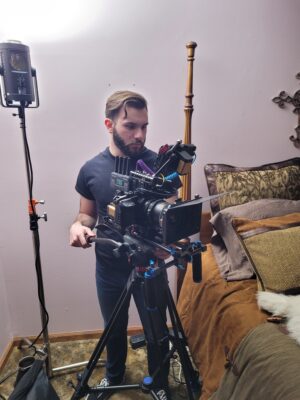 Image of Gavin Hebert operating film camera on film set.