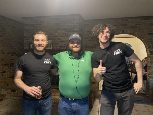 Image of three people on film set. Center figure has director/sound director headphones around neck.