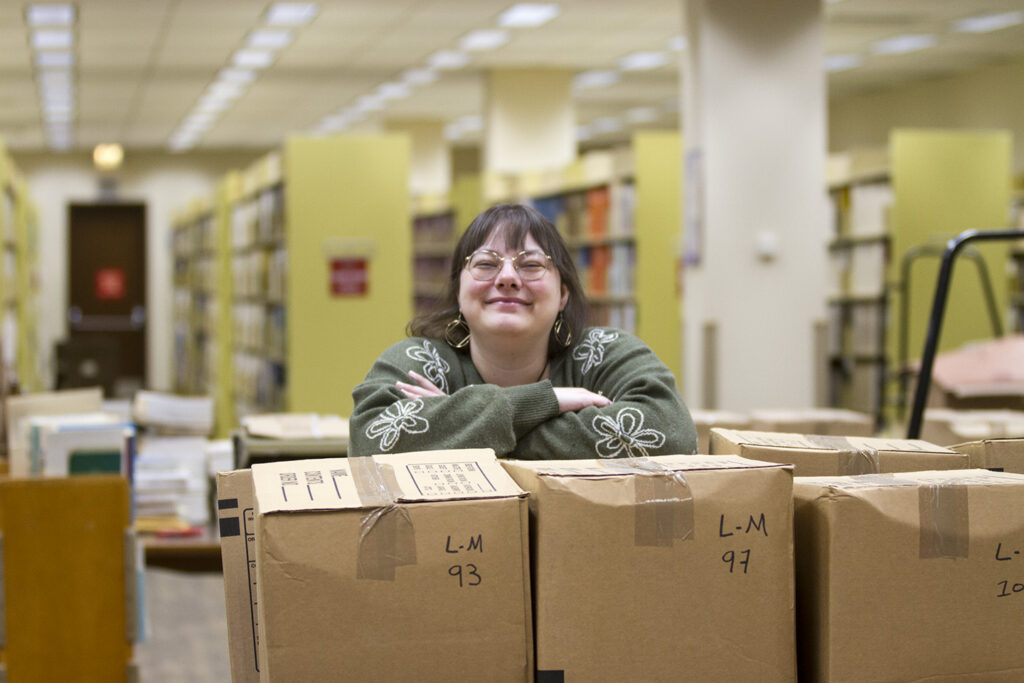 Nicholls Librarian Jade Gregory Hornback poses with some of the boxes of books and material she is working with to get back on the shelves.