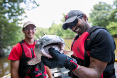picture of biology professor holding a large catfish on the bayou