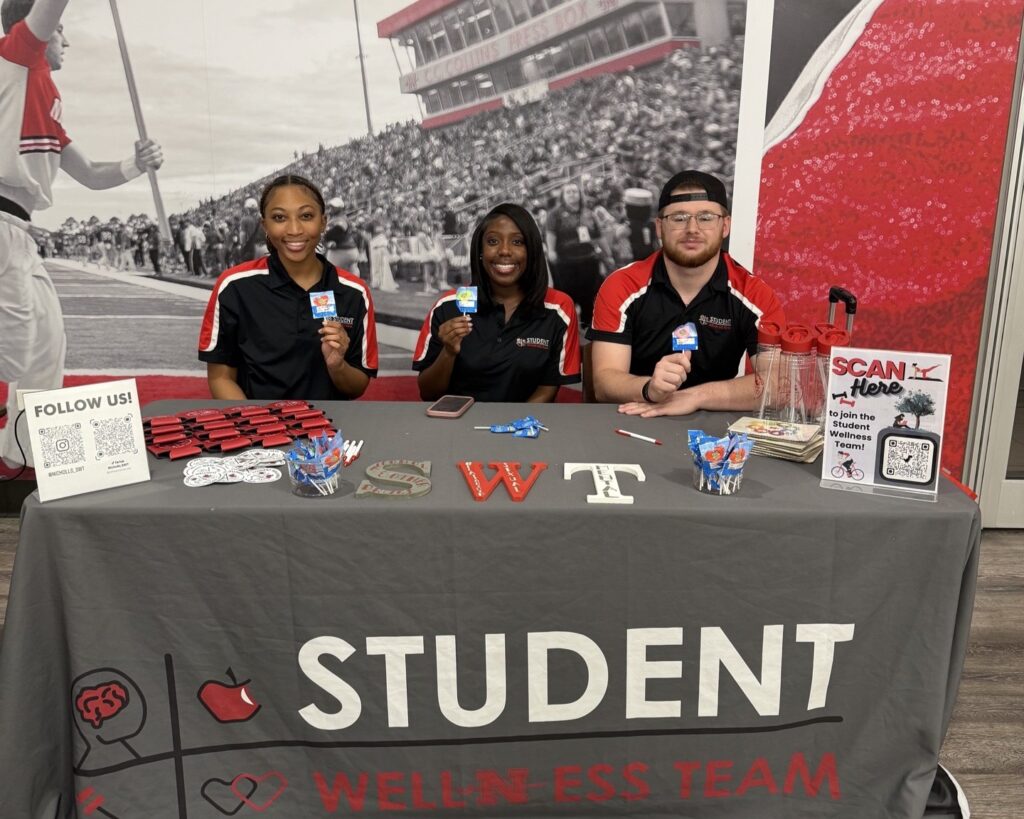 Three students sitting at an information table.
